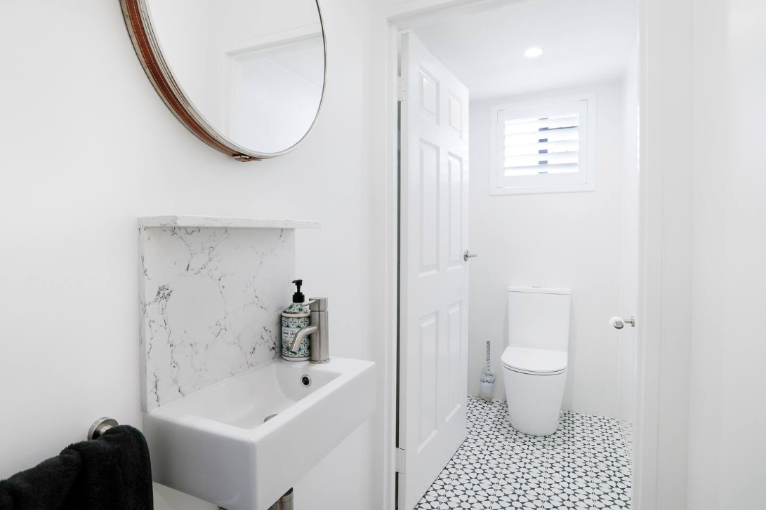A bathroom with a sink , toilet and mirror.