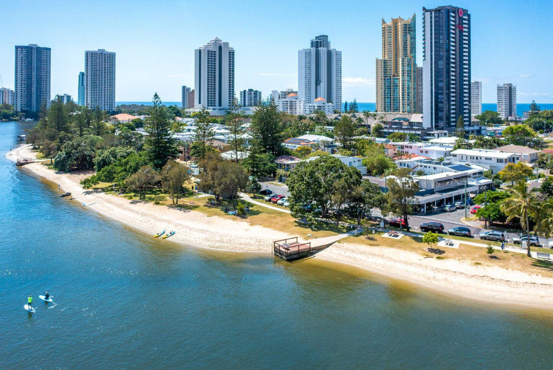 An aerial view of a beach next to a river with a city in the background.