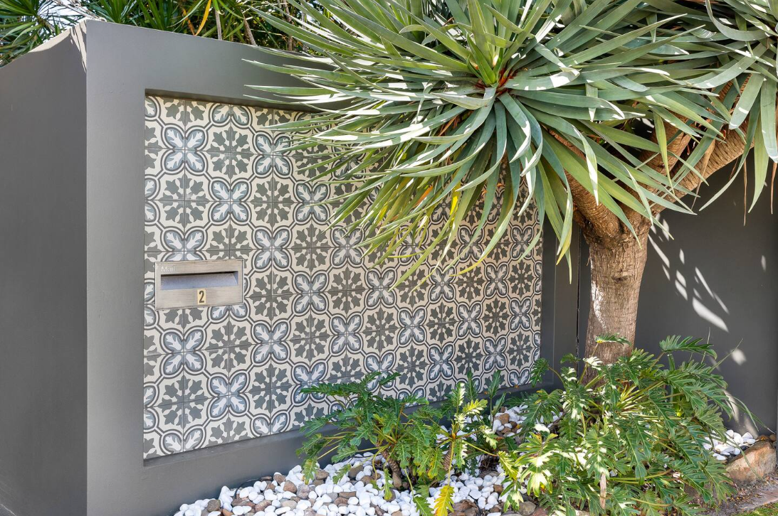 A tree is standing next to a wall with a mailbox on it.