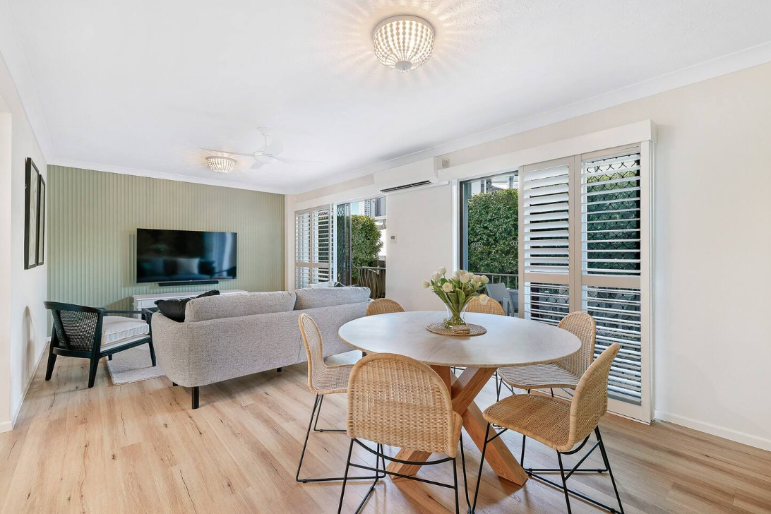 A living room with a table and chairs and a flat screen tv.