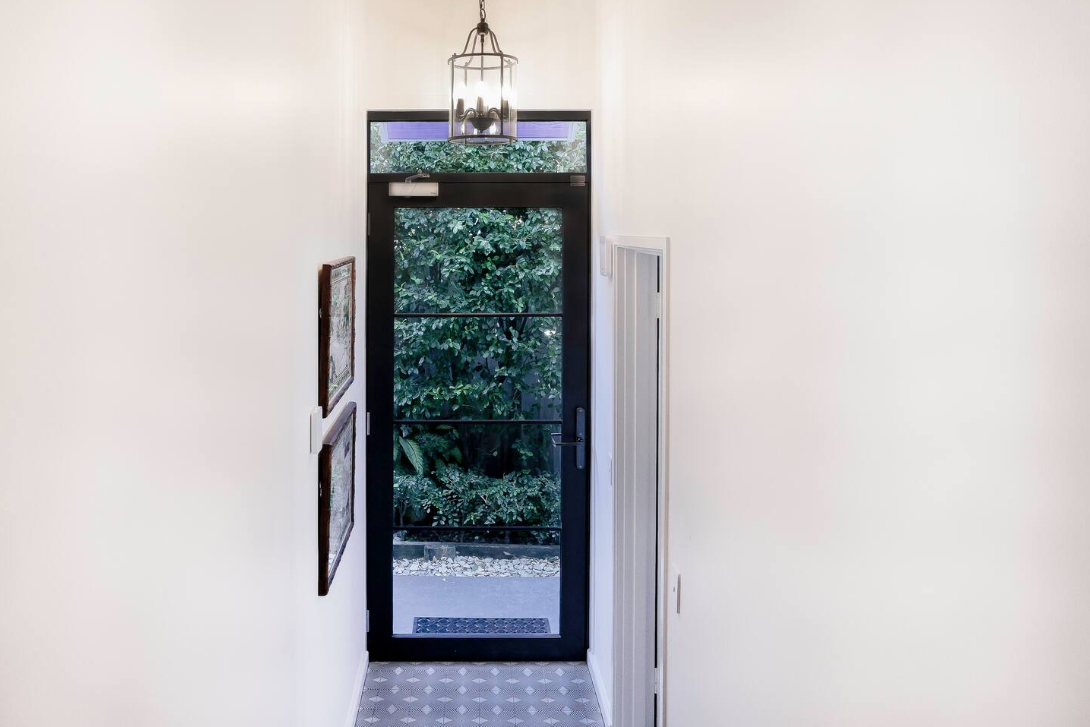 A hallway with a black door and a lantern hanging from the ceiling.