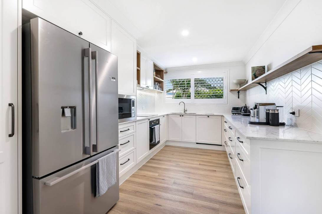 A kitchen with stainless steel appliances and white cabinets.