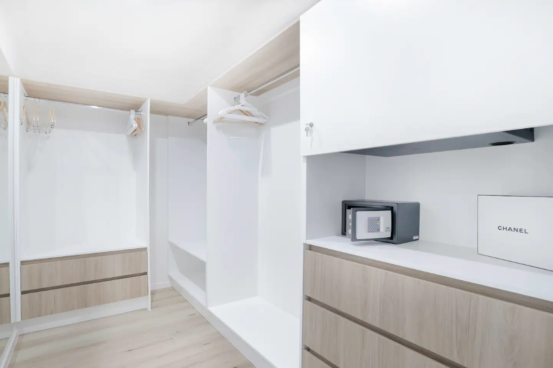 A walk in closet with white cabinets and wooden drawers.