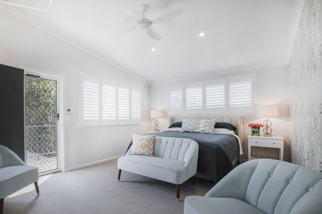 A bedroom with a bed , chairs , a couch and a ceiling fan.