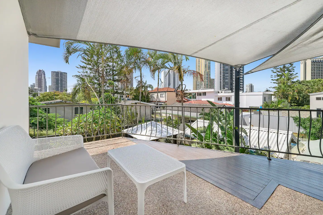 There is a balcony with a table and chairs and a view of the city.