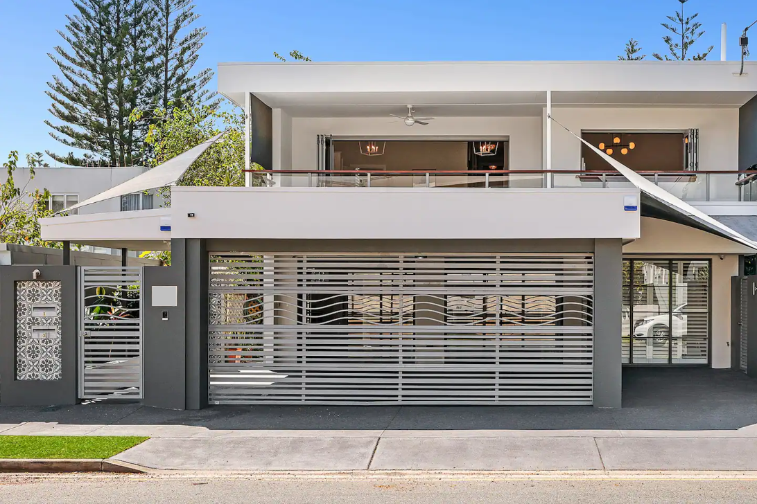 A large white house with a gray fence and a garage door