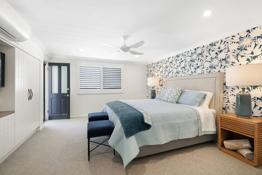 A bedroom with a bed , nightstand , lamps and a ceiling fan.