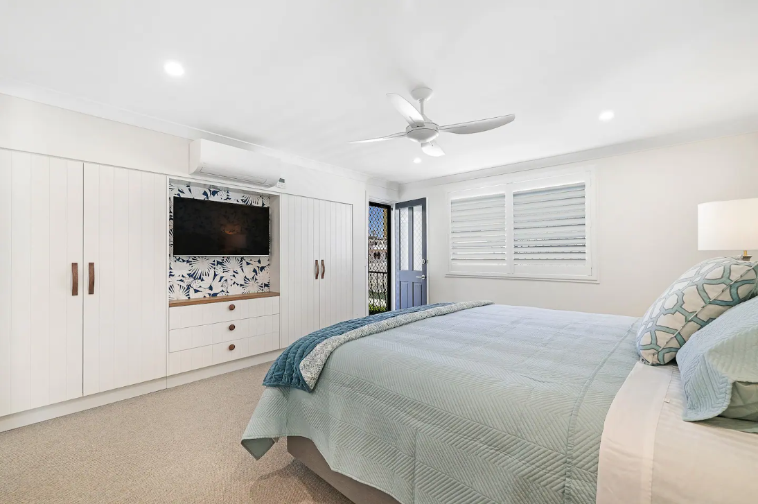 A bedroom with a king size bed , a flat screen tv , and a ceiling fan.