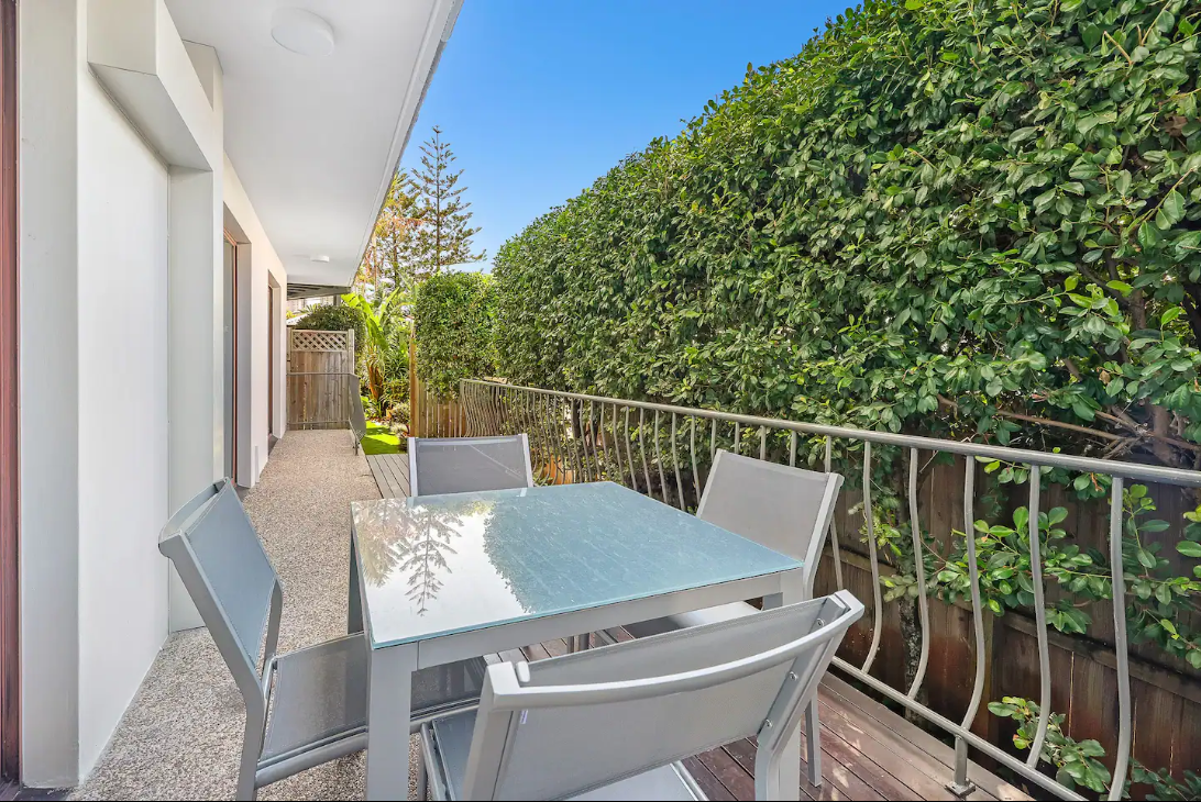 There is a table and chairs on the balcony of a house.
