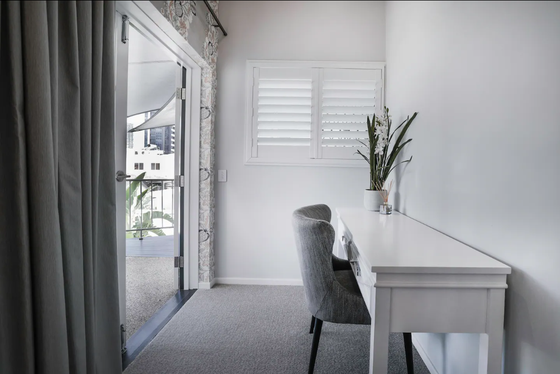 There is a desk and chair in the corner of the room.