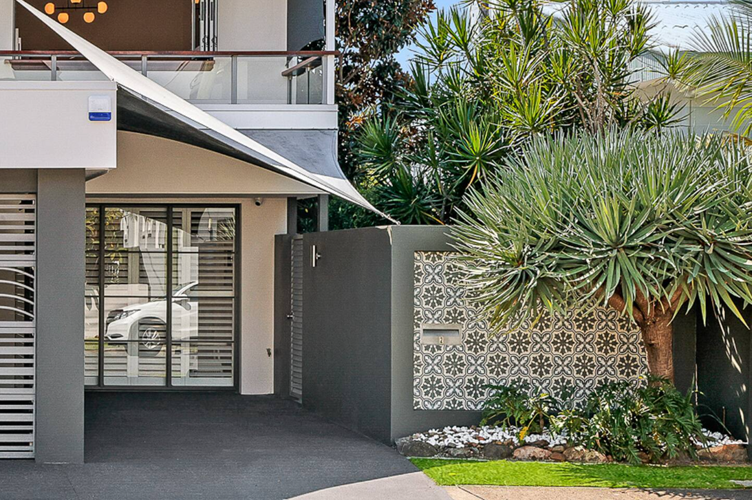 The front of a house with a fence and a tree in front of it.