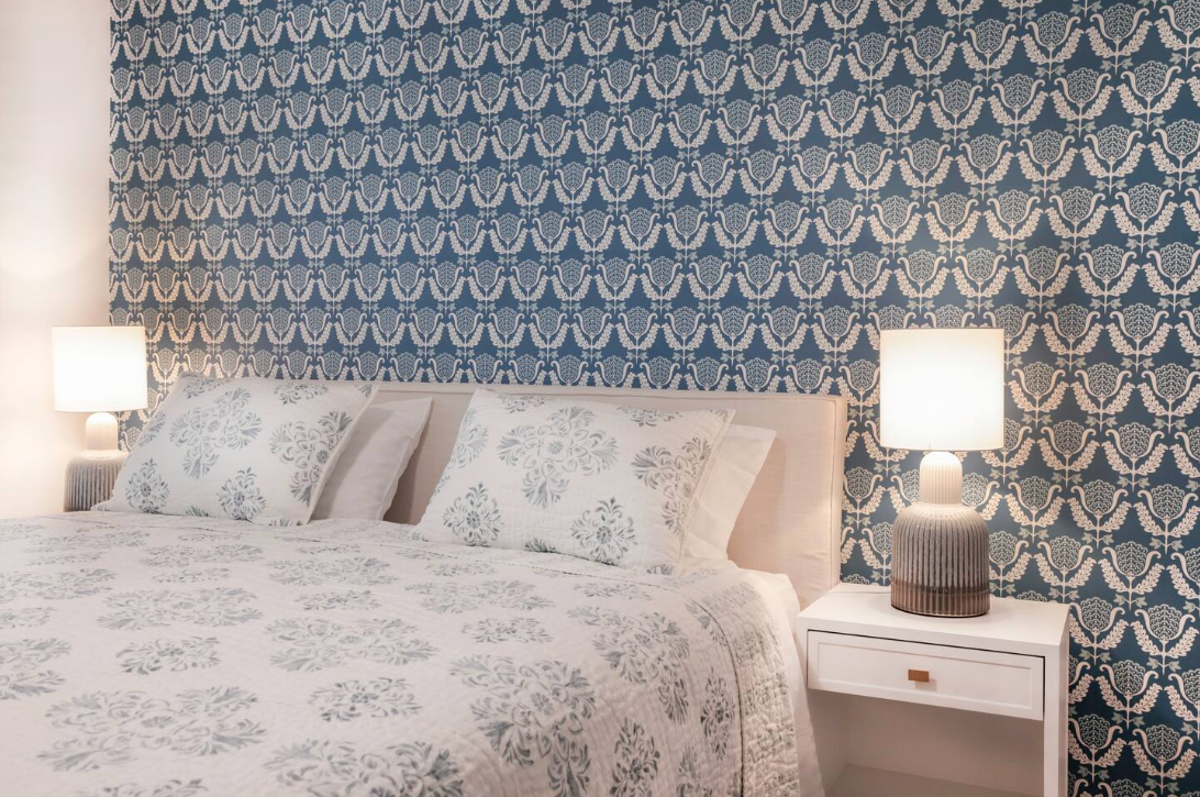 A bedroom with a bed , nightstand , and lamps.