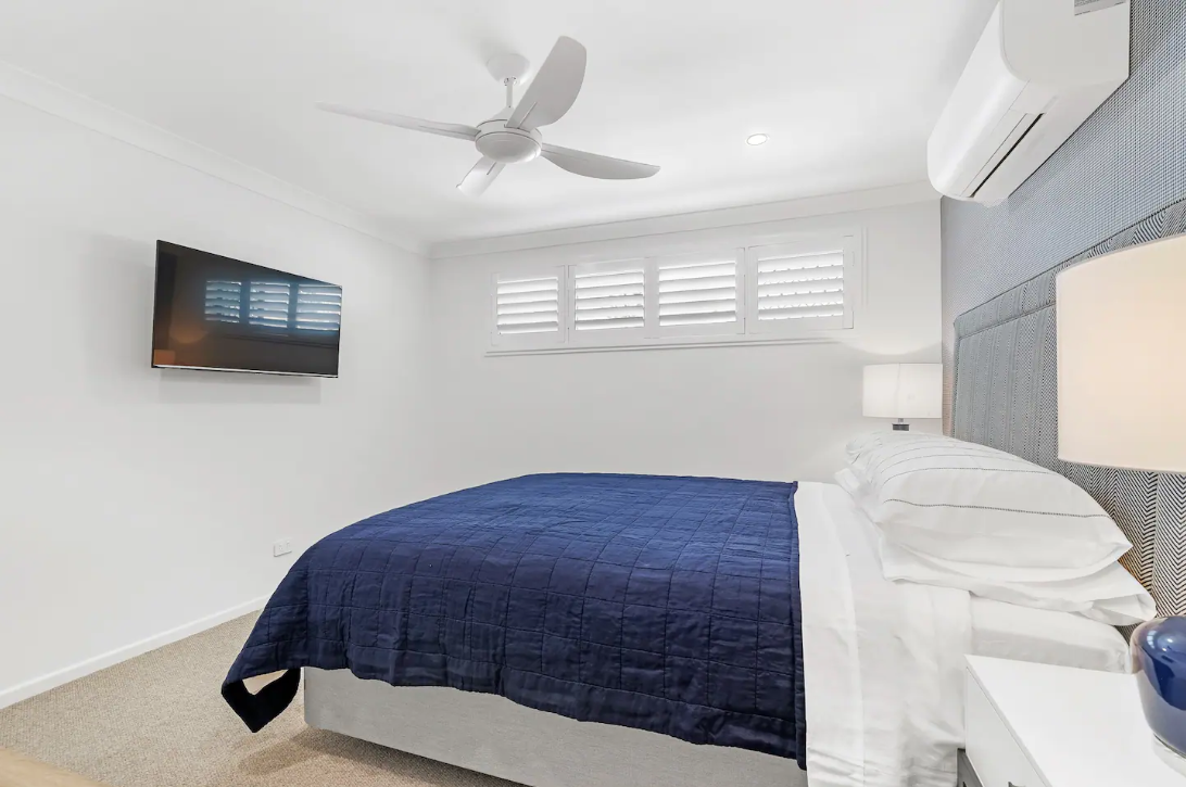 A bedroom with a bed , television and ceiling fan.