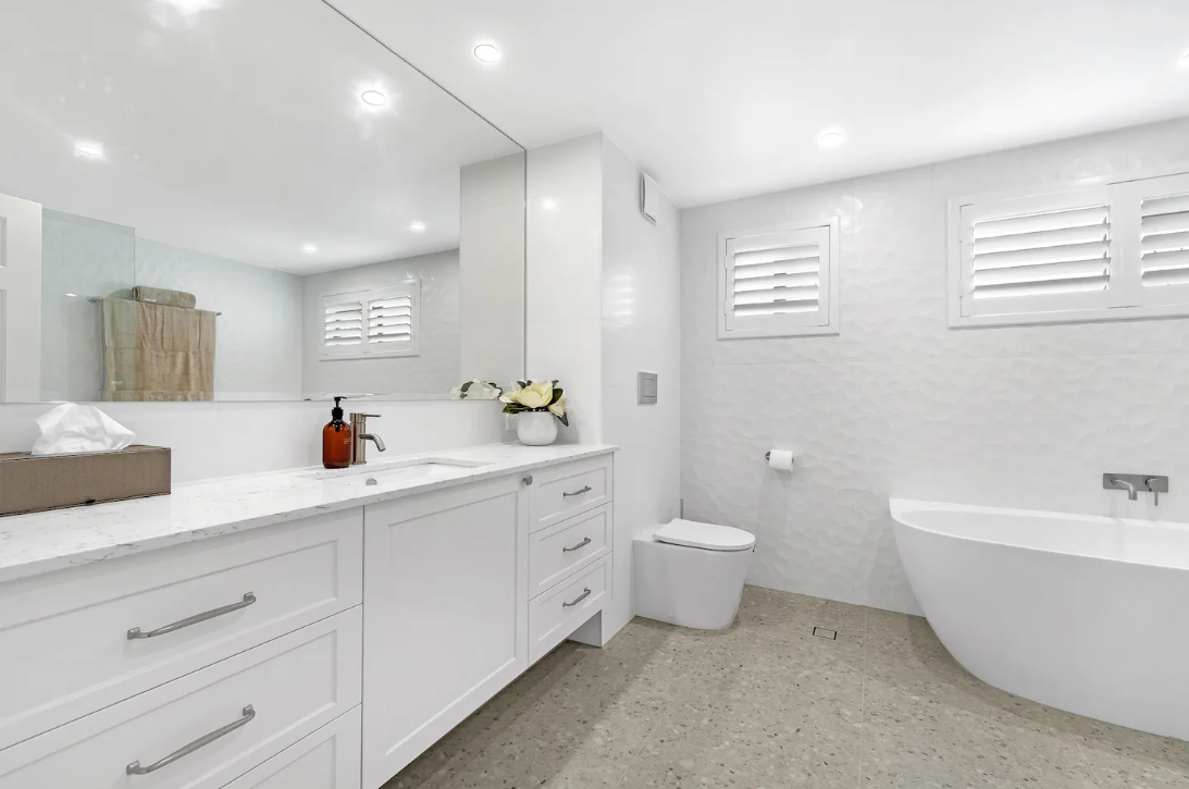 A bathroom with a tub , sink , toilet and mirror.
