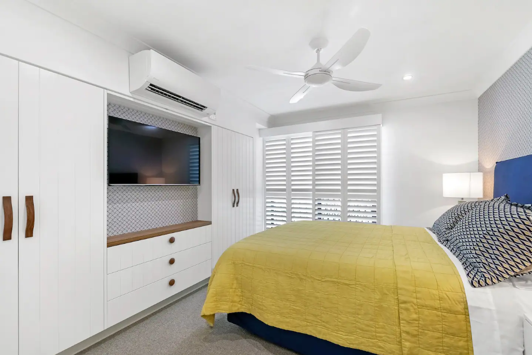 A bedroom with a bed , television , and ceiling fan.