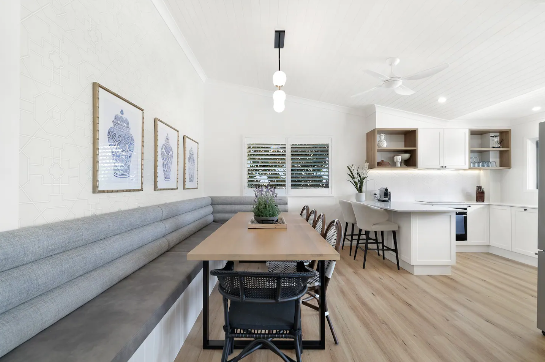 A dining room with a table and chairs and a bench.