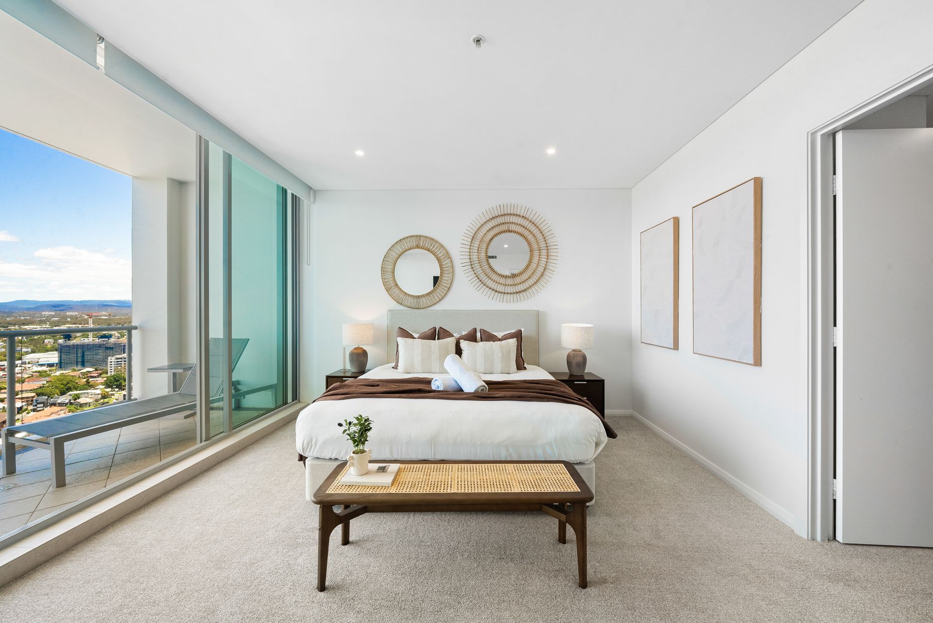 A bedroom with a large bed , a bench , and a balcony.