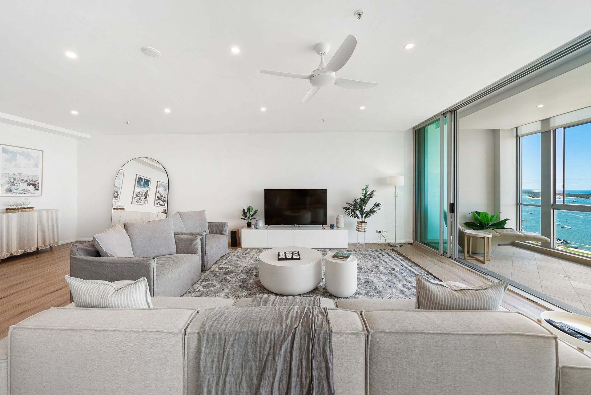 A living room with a couch , chairs , a television and a ceiling fan.