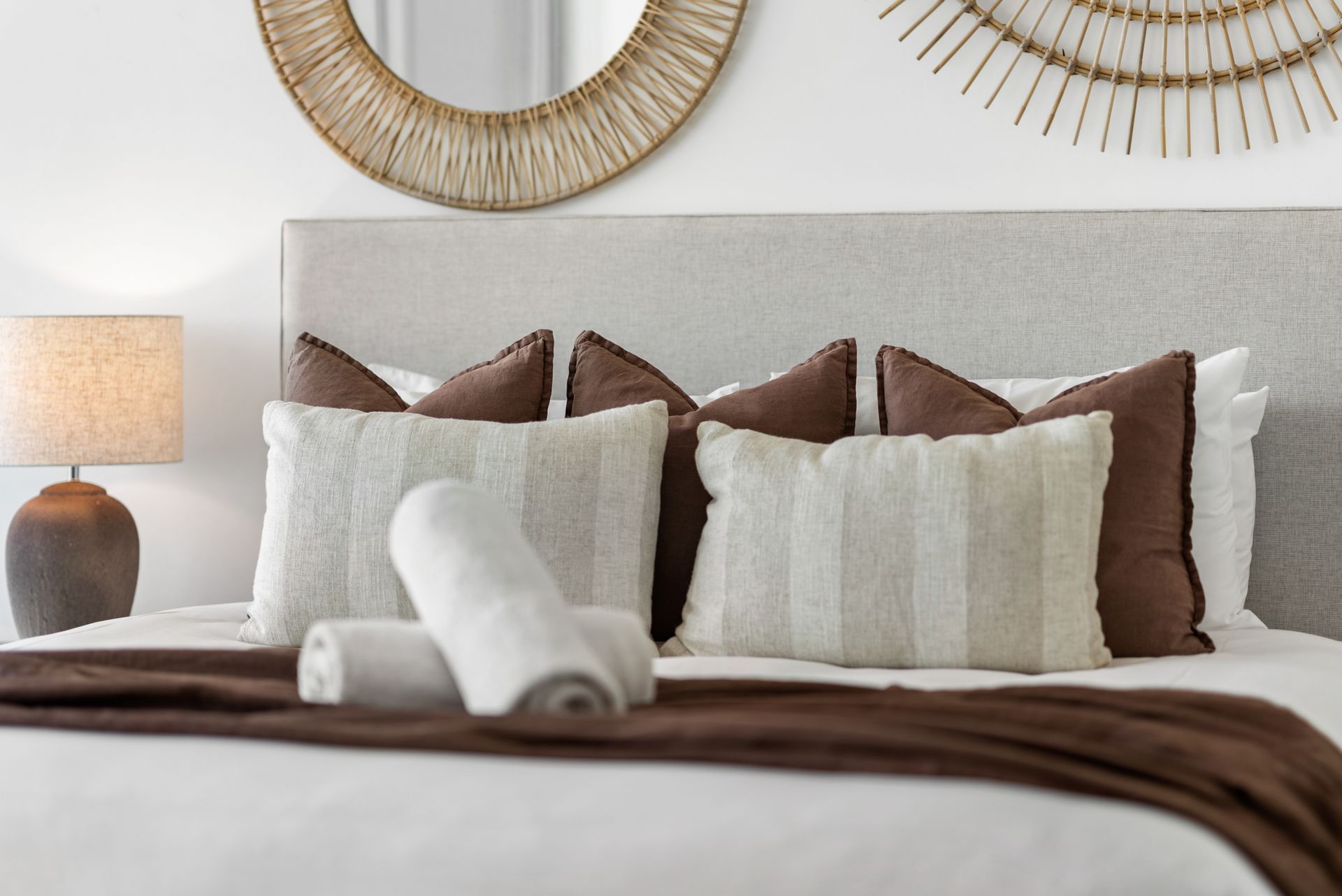 A bedroom with a bed , pillows , a lamp and a mirror.