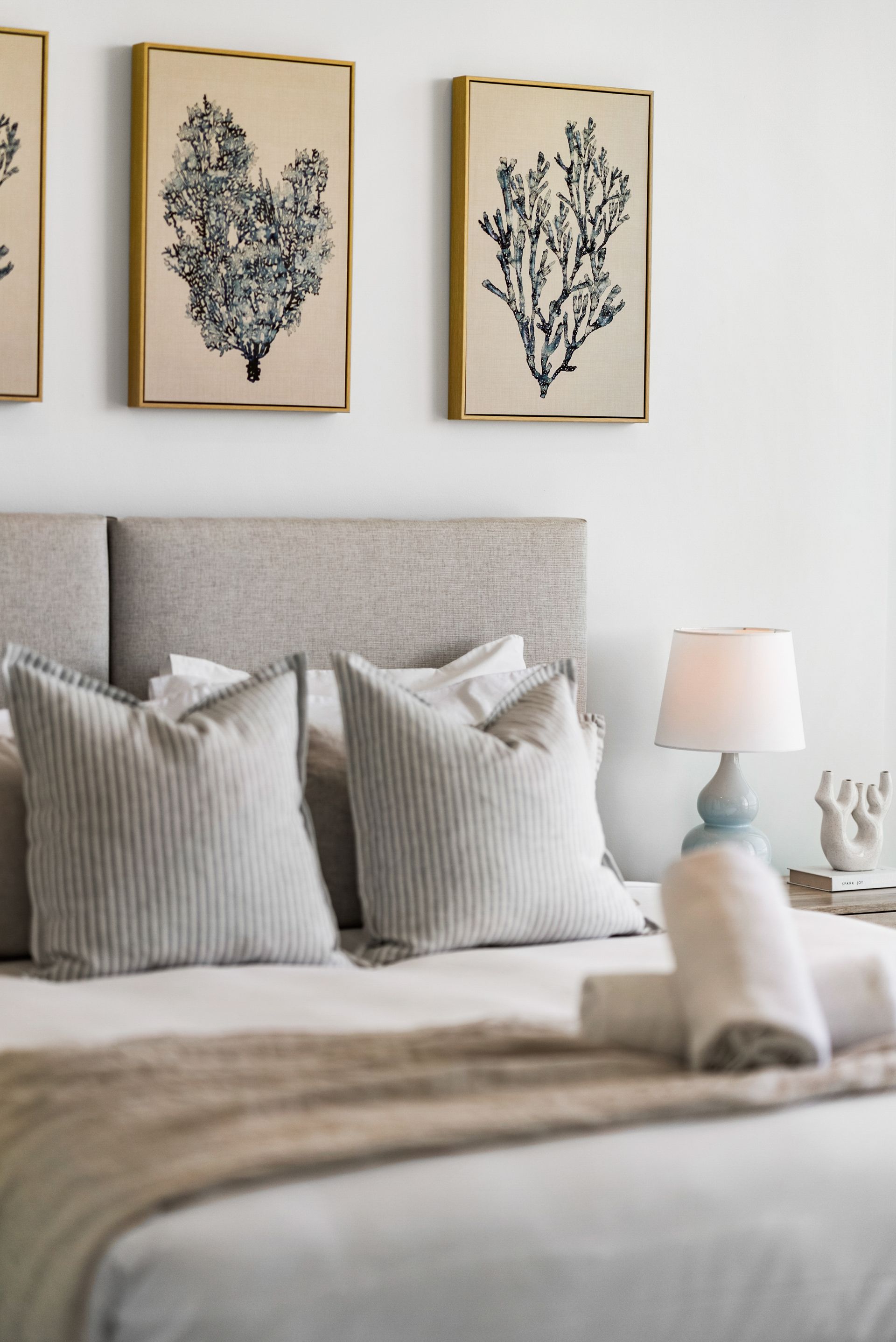 There are three paintings on the wall above the bed.