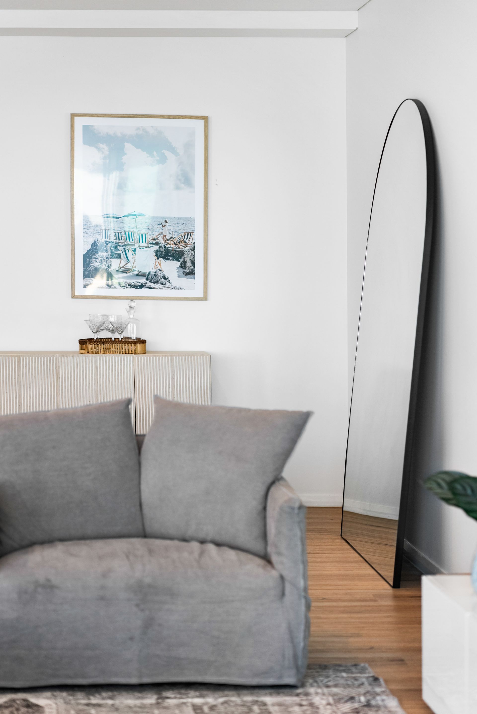 A living room with a couch , mirror and painting on the wall.