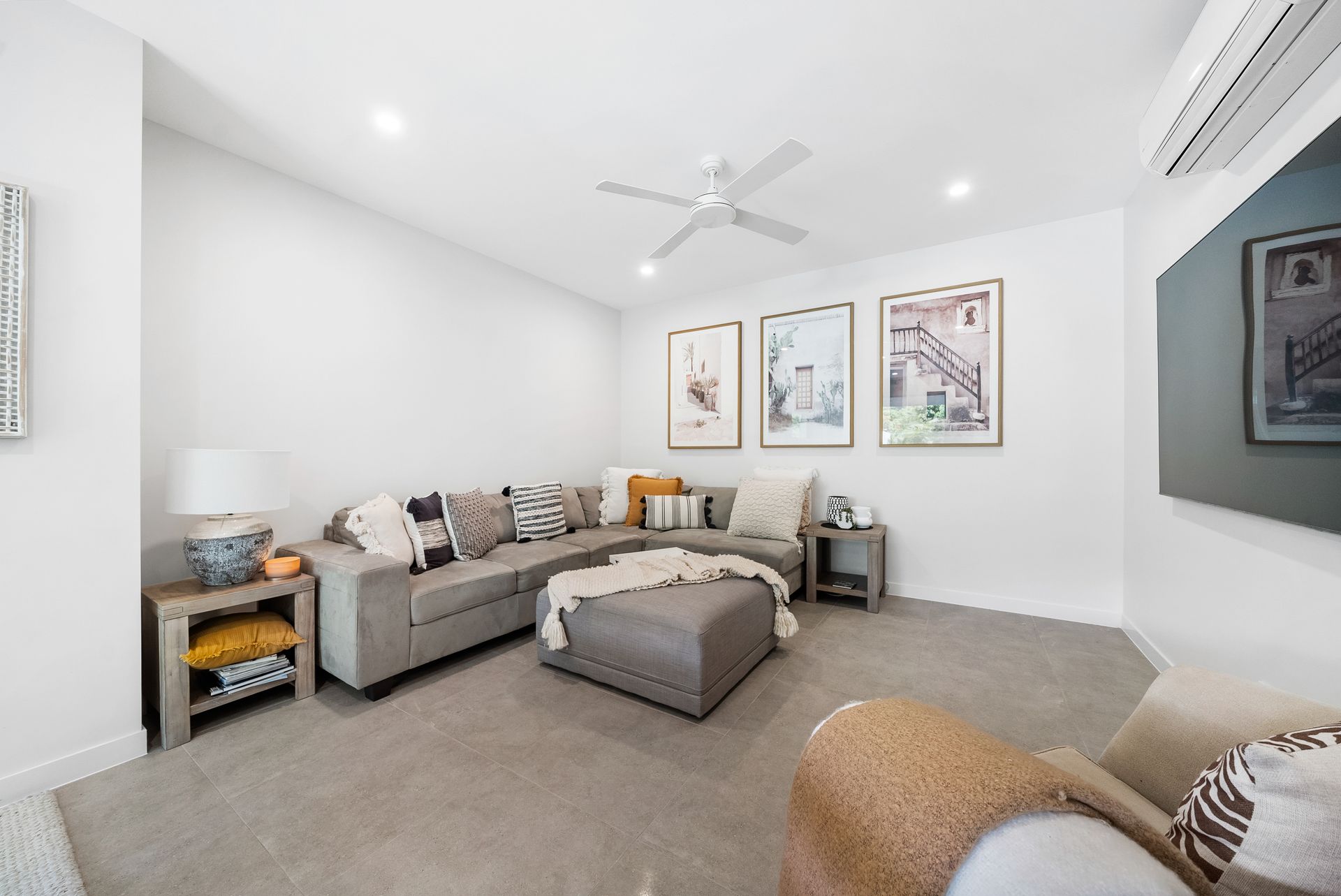 A living room with a large sectional couch and a ceiling fan.