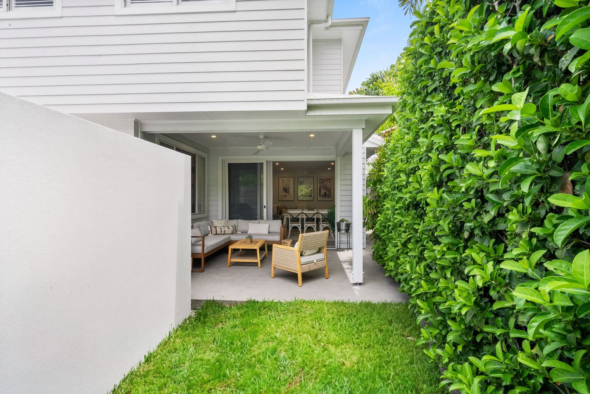 A white house with a patio and a lush green yard.