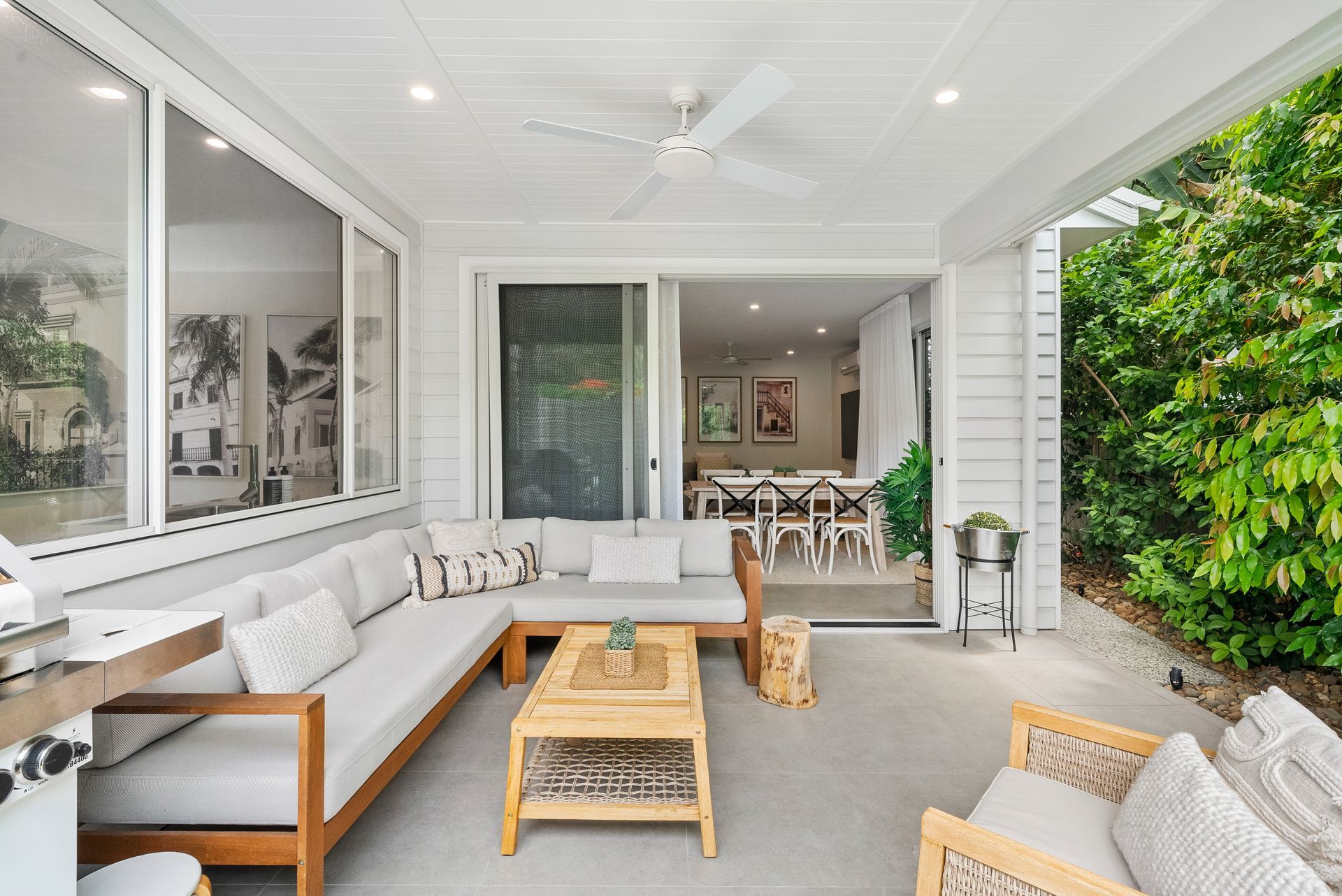 A patio with a couch , chairs , a table and a ceiling fan.
