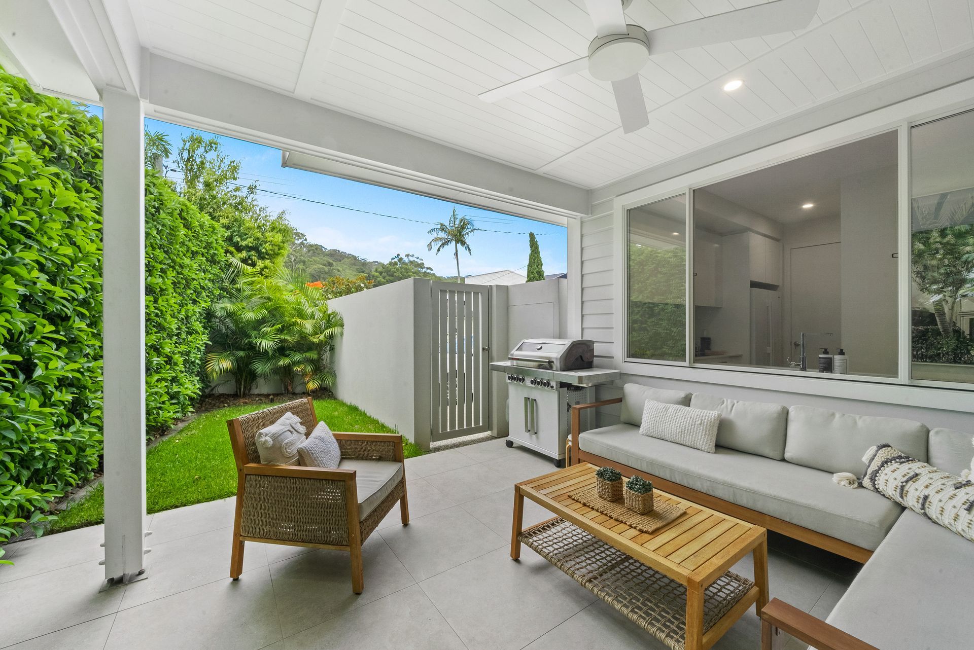 A patio with a couch , chairs , table and grill.