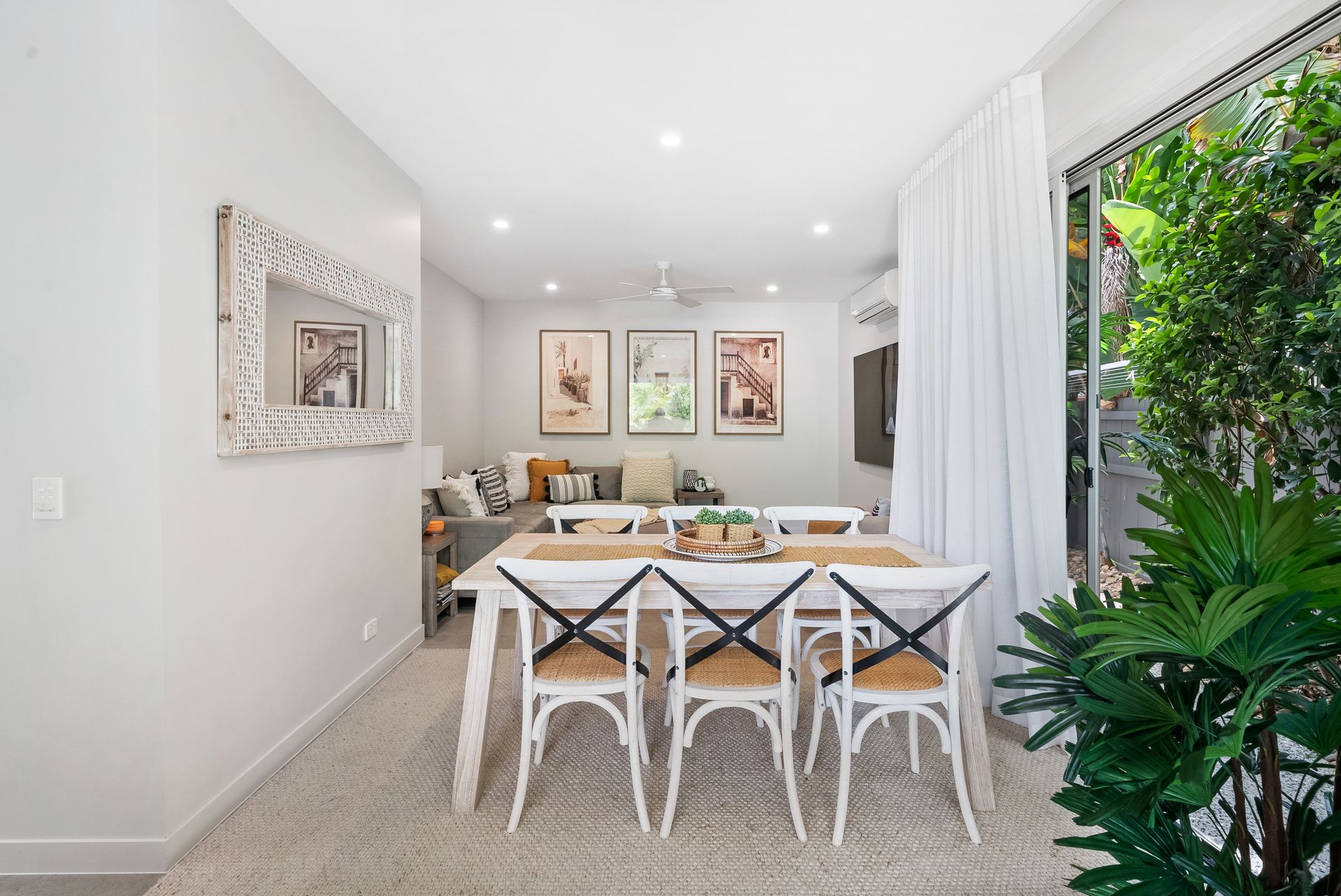 A living room with a dining table and chairs and a sliding glass door.