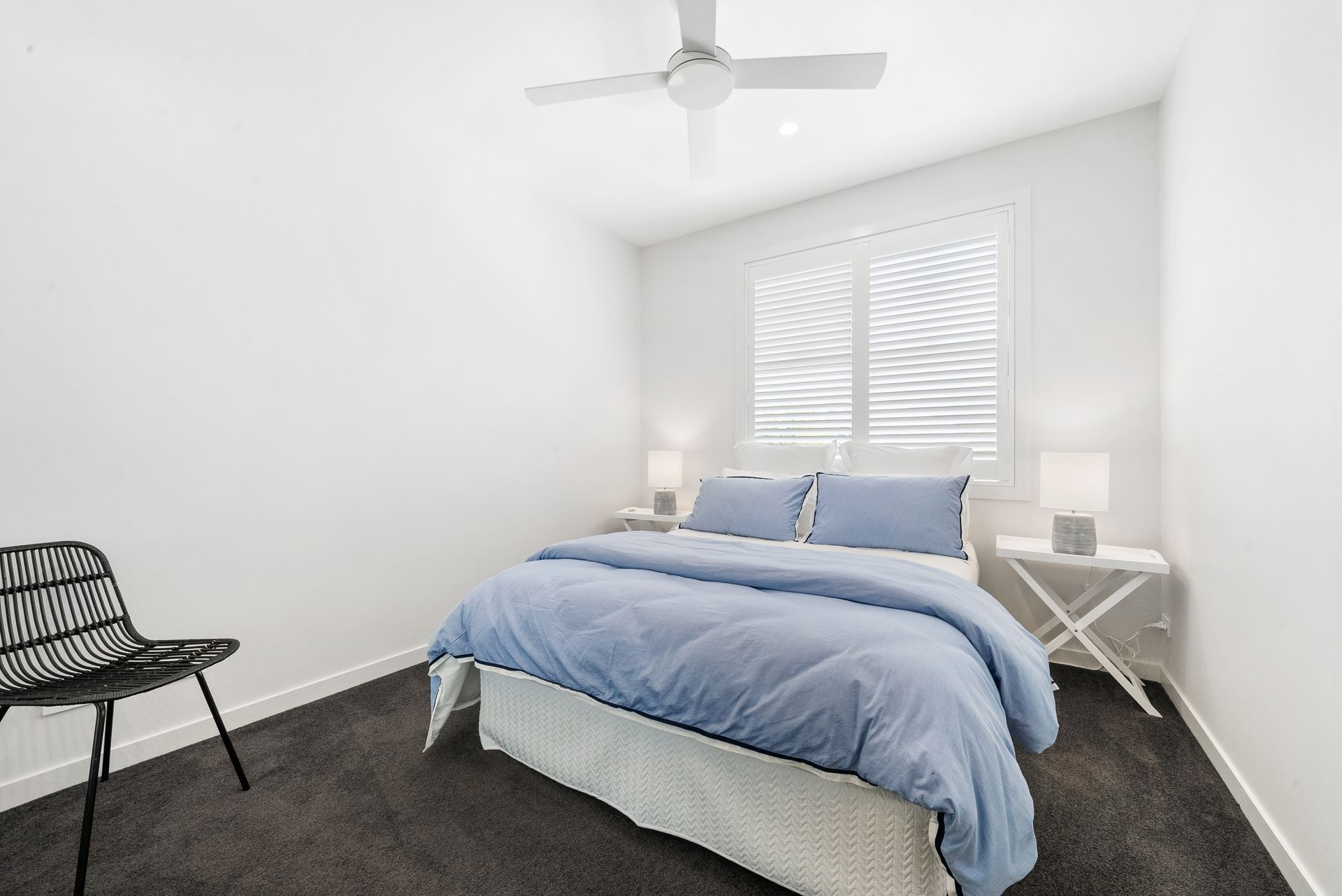 A bedroom with a bed , chair , nightstand and ceiling fan.