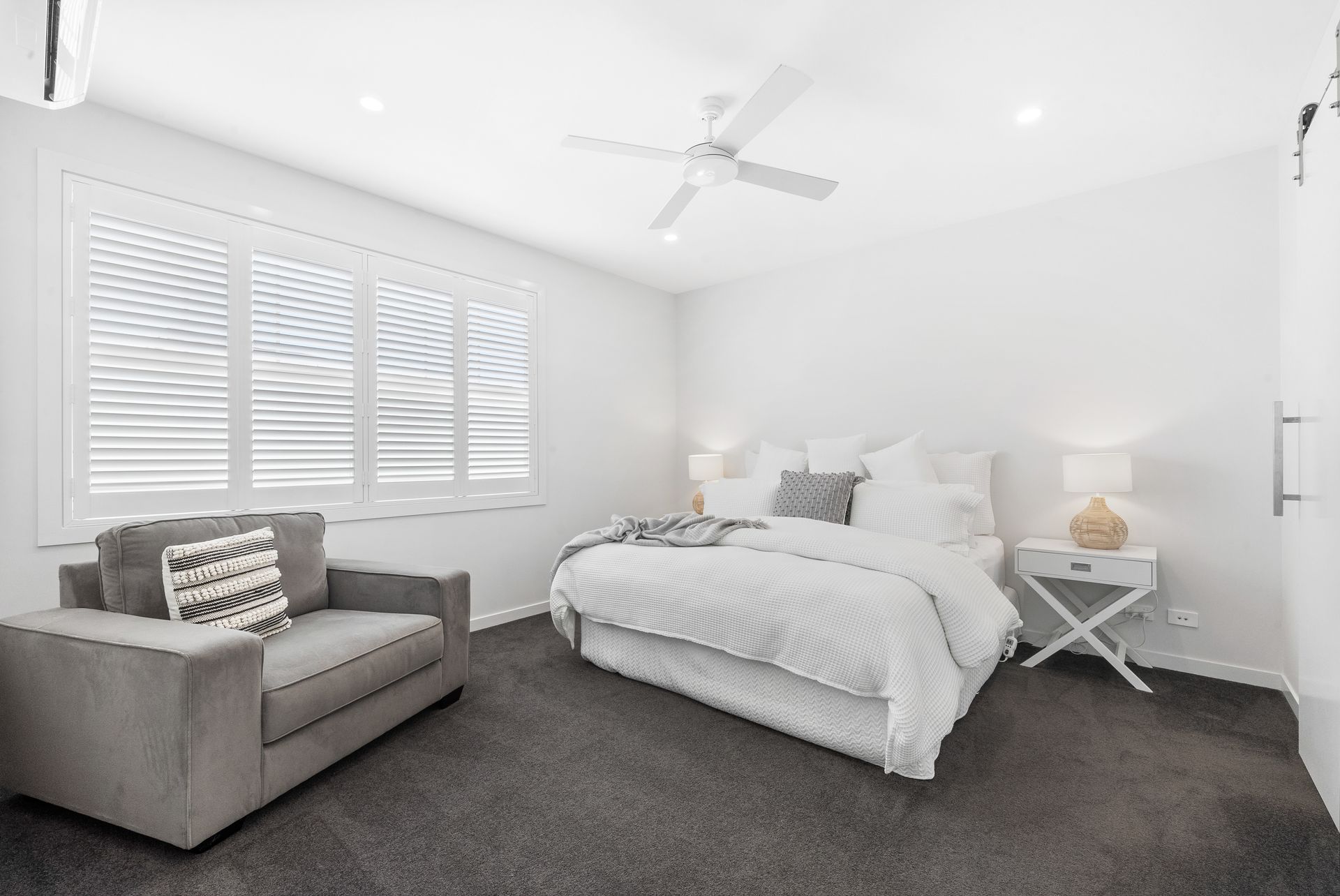 A bedroom with a bed , chair , nightstand and ceiling fan.