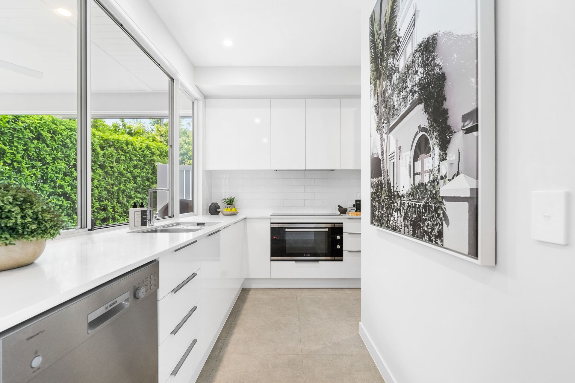 A kitchen with white cabinets and stainless steel appliances and a picture on the wall.