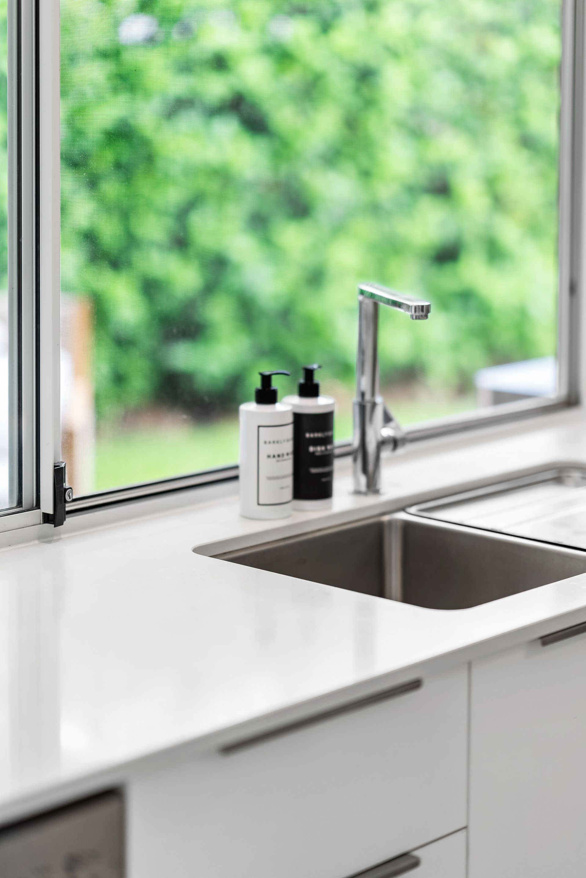 A kitchen sink with two bottles of soap on top of it.