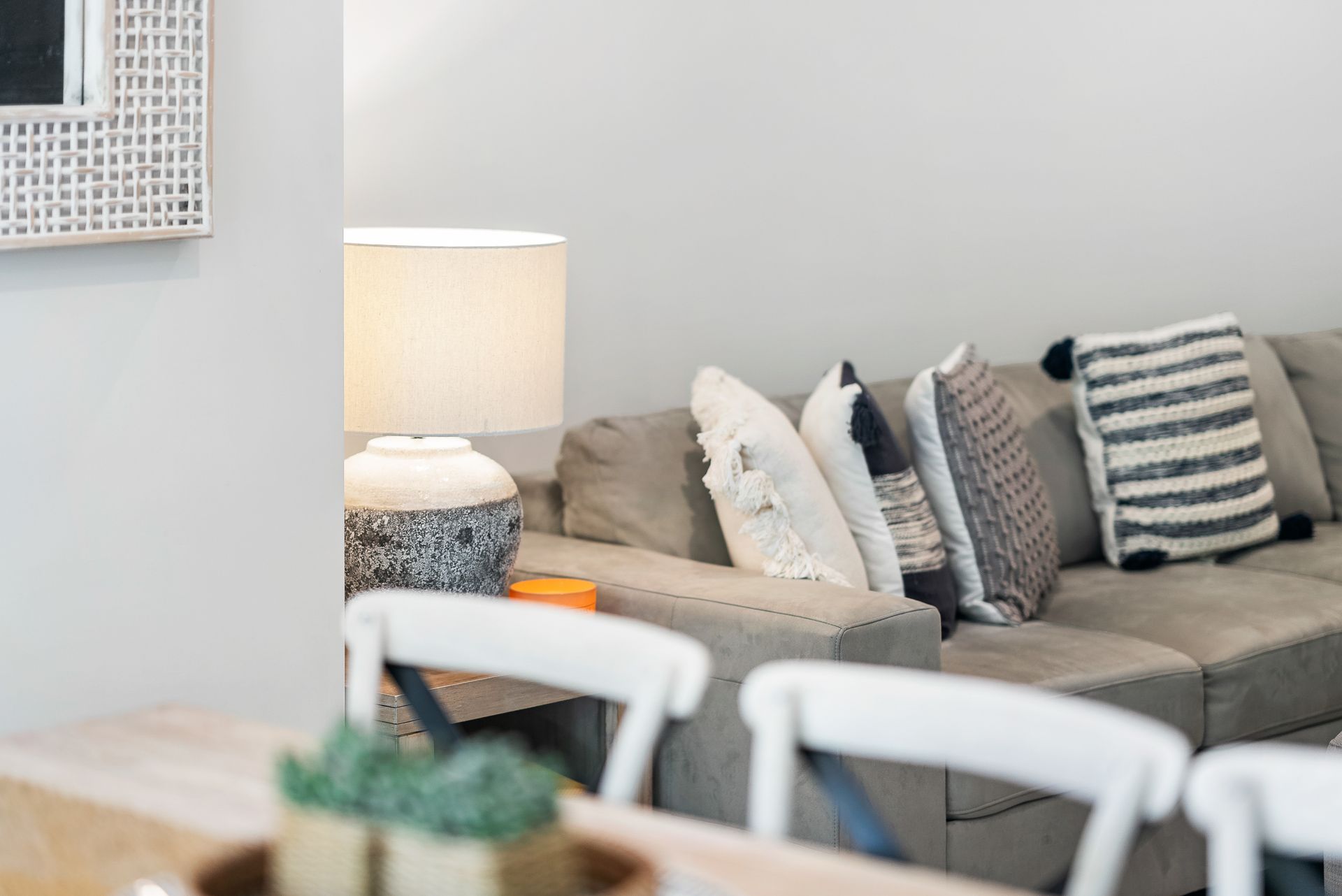 A living room with a couch , chairs , table and lamp.