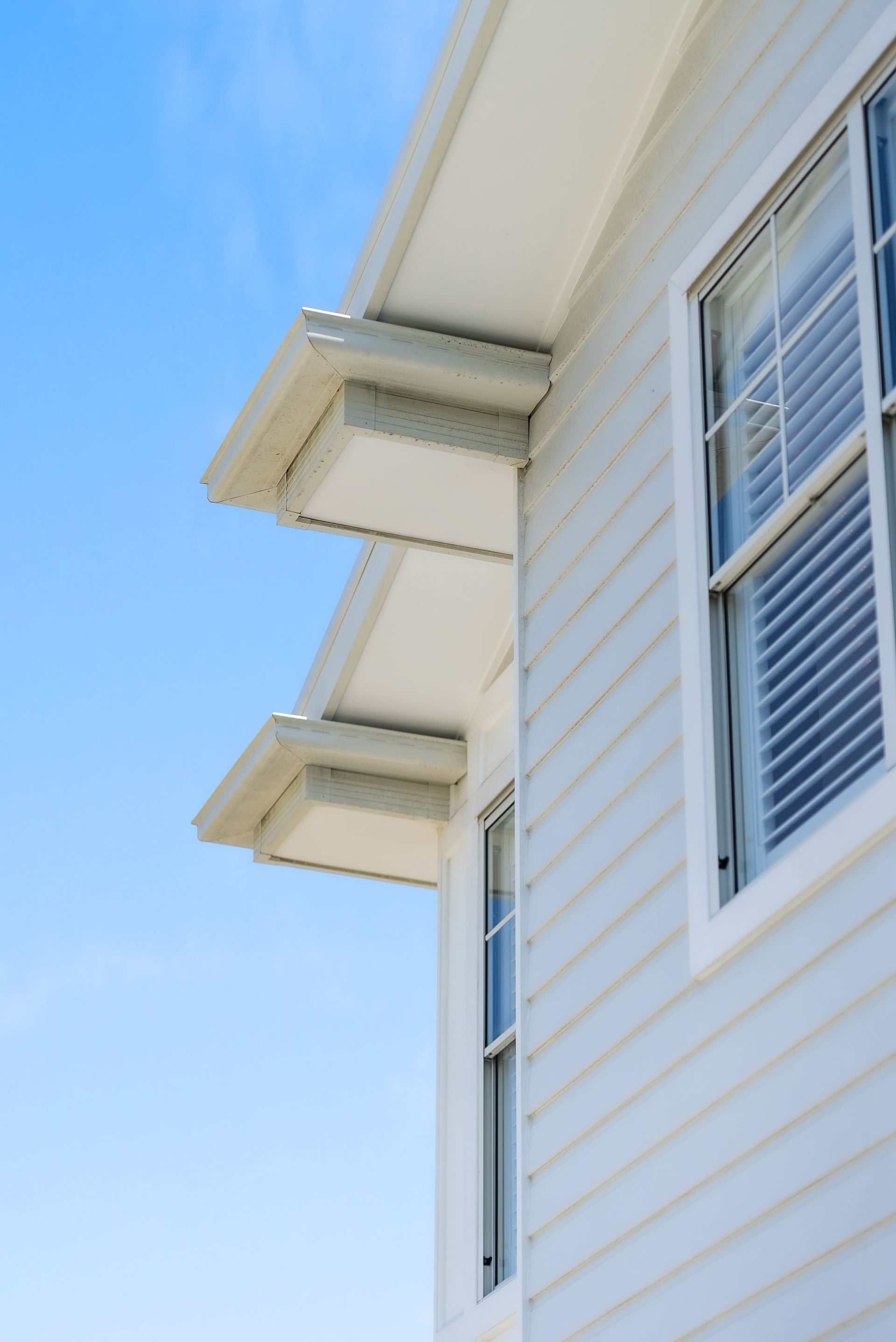 A white house with a lot of windows and a blue sky in the background.