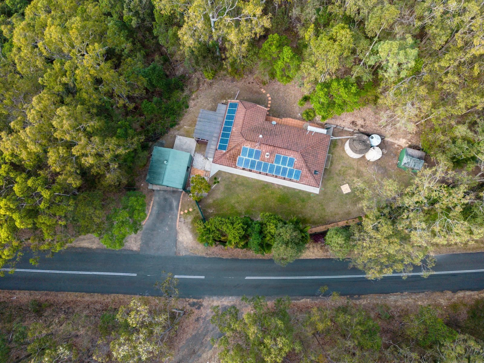 An aerial view of a house surrounded by trees and a road.