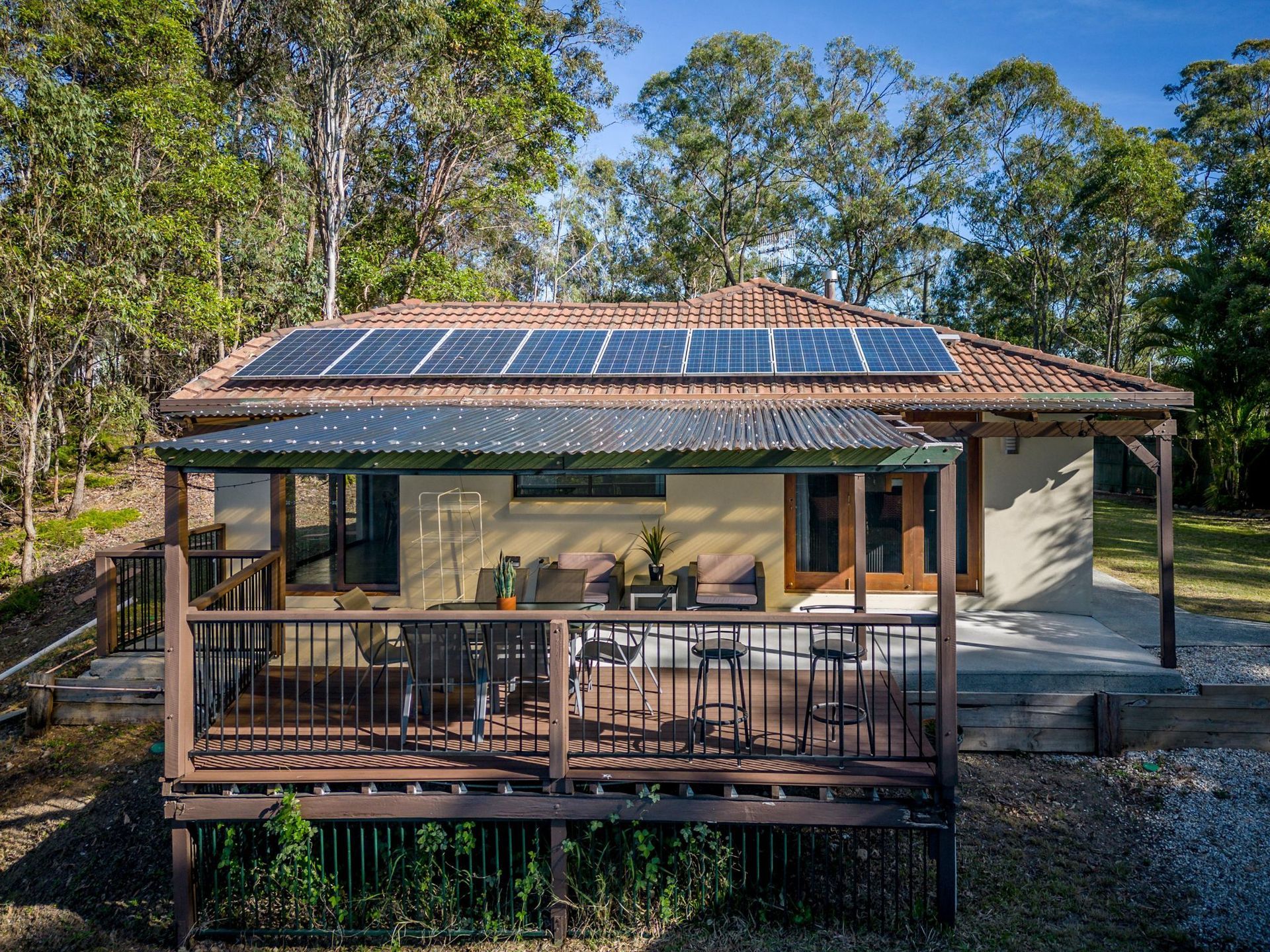 A small house with a large deck and solar panels on the roof.