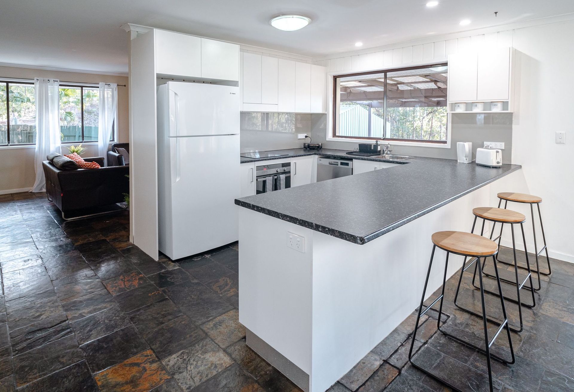 A kitchen with a large island and stools in a house.
