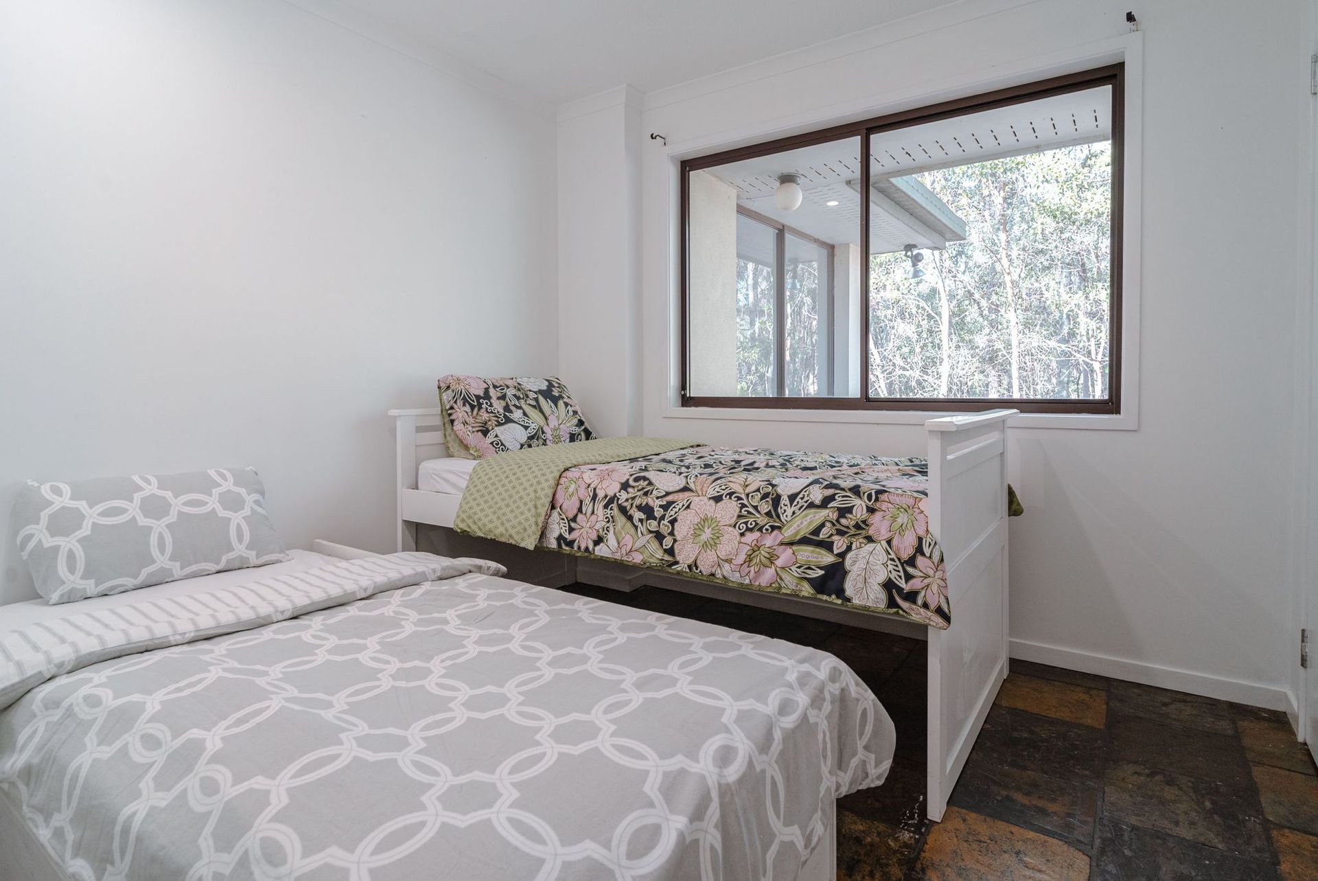A bedroom with two beds and a large window.