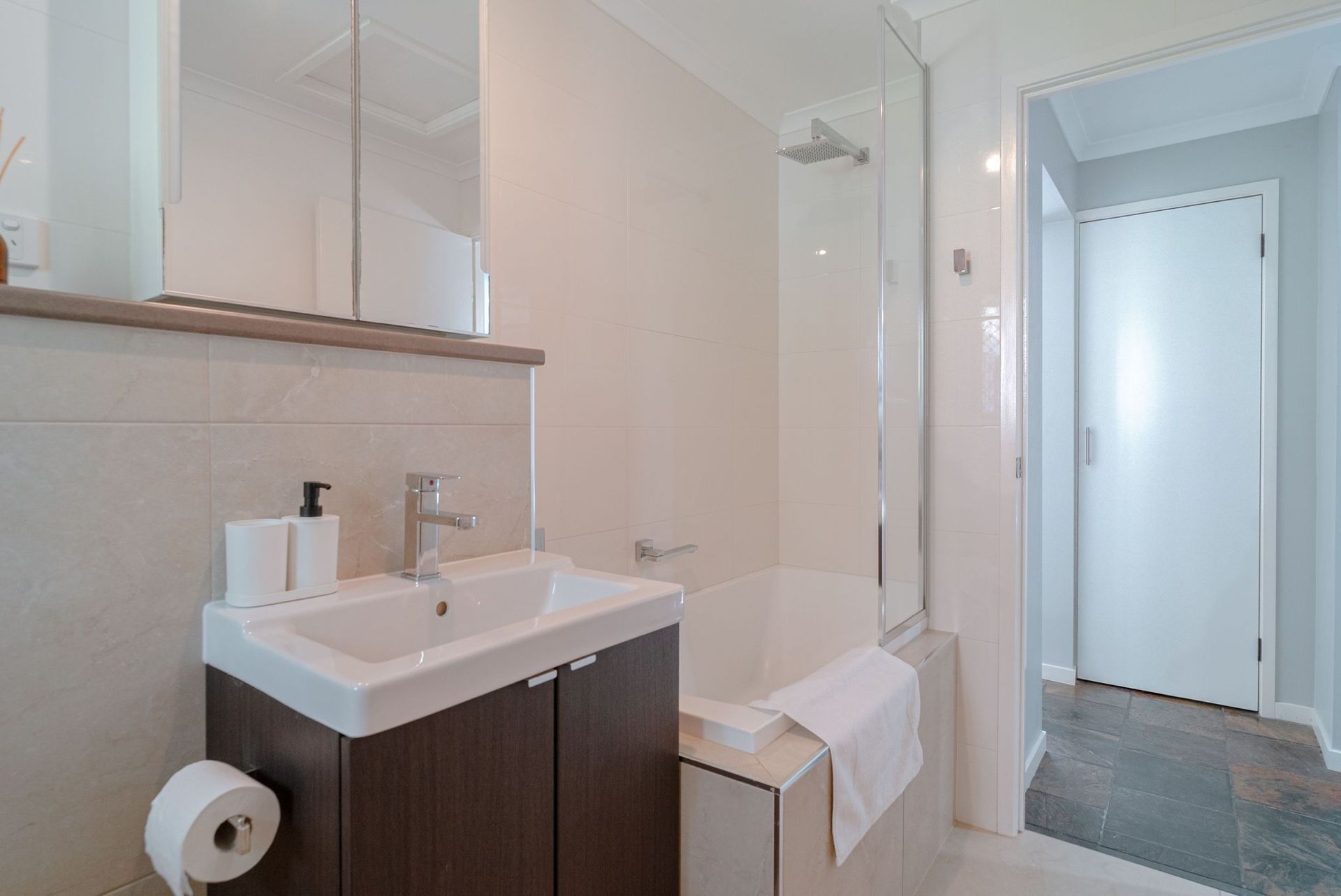A bathroom with a sink , tub and mirror.