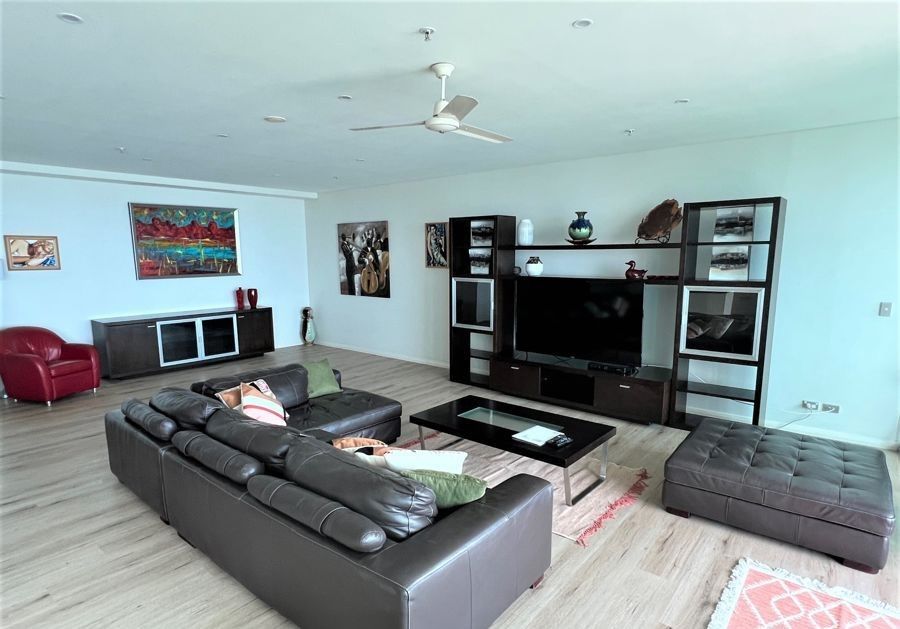 A woman is laying on a couch in a living room with a ceiling fan.