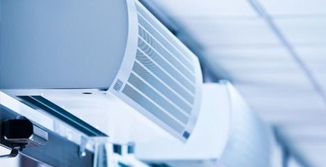 Unidad de aire acondicionado con filtro abierto, emitiendo aire frío.