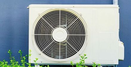 Unidad de aire acondicionado de color blanco montada en una pared con un ventilador en el frente.