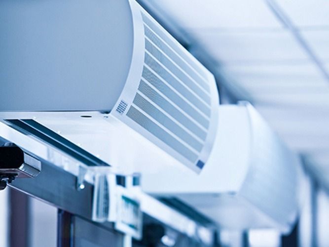 Unidades de aire acondicionado blancas montadas en una pared con filtros visibles.