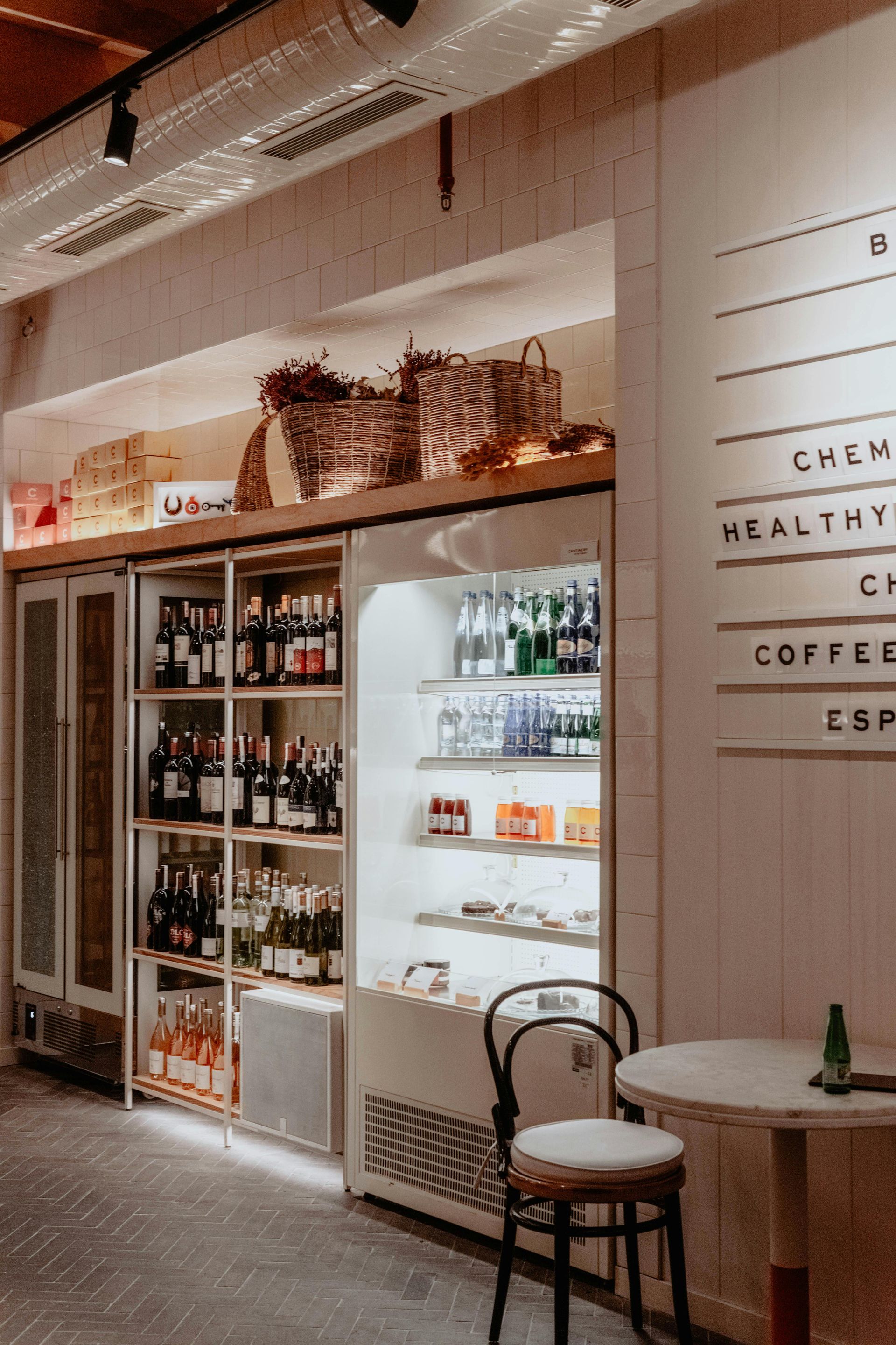Kahvilan sisustus, jossa on kylmien juomien teline, viiniä ja istuinalue. Puiset hyllyt ja ruokalista.