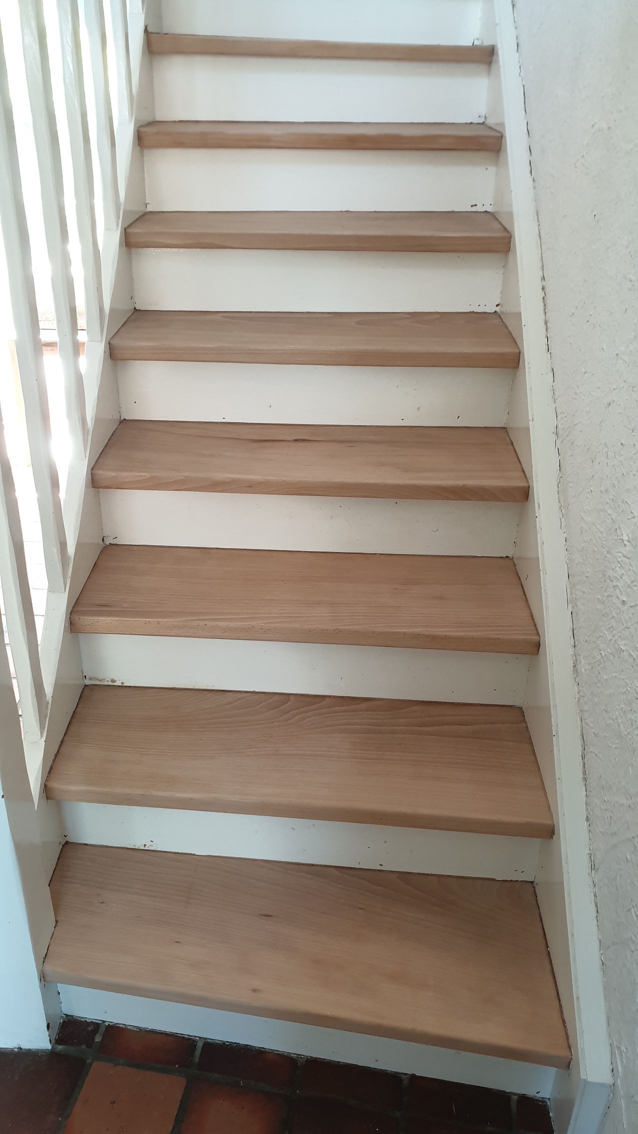 Escalier en bois avec rampe et contremarches blanches.