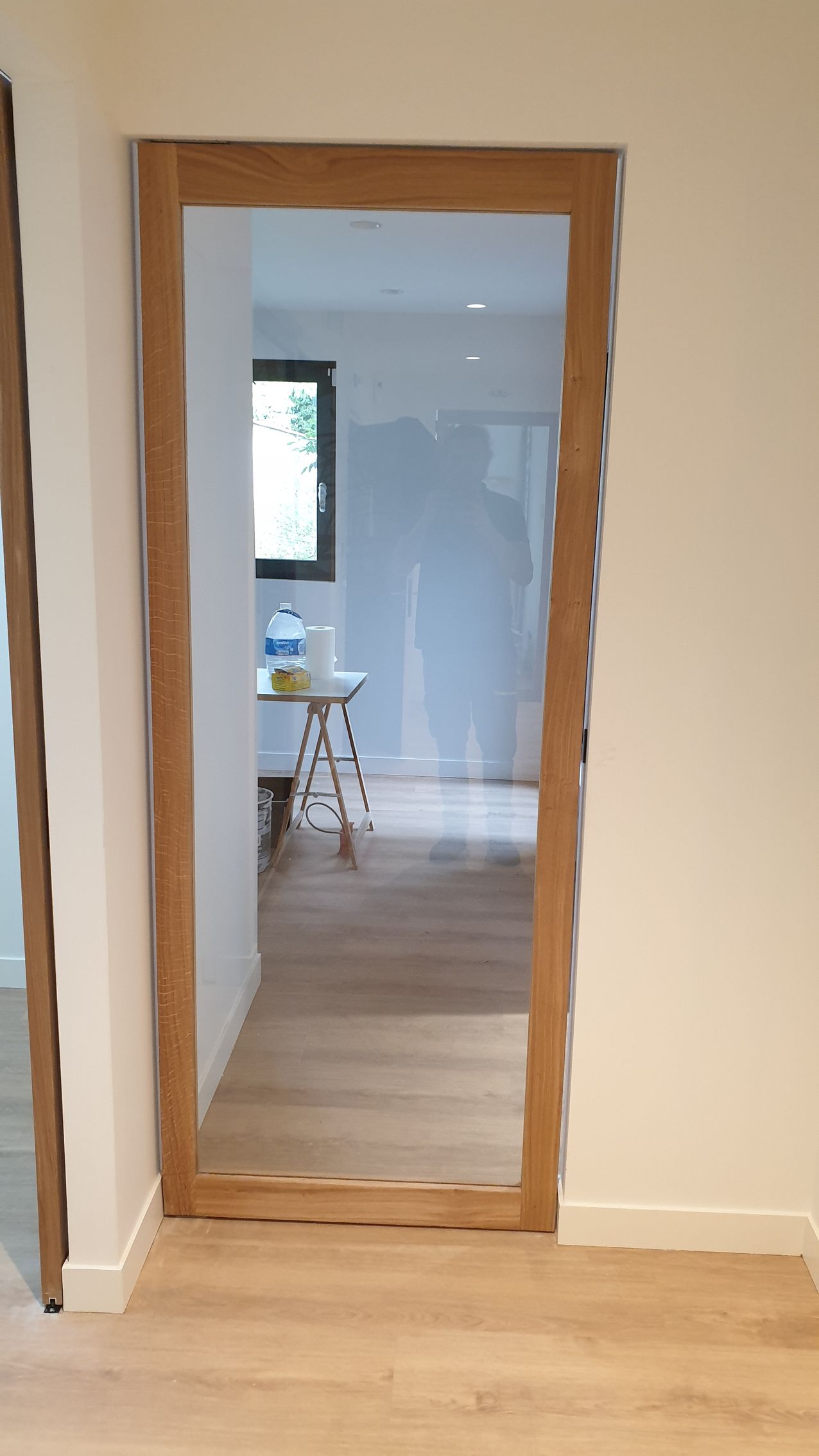 Porte à cadre en bois, murs et sol clairs, vue intérieure, menant à une autre pièce.