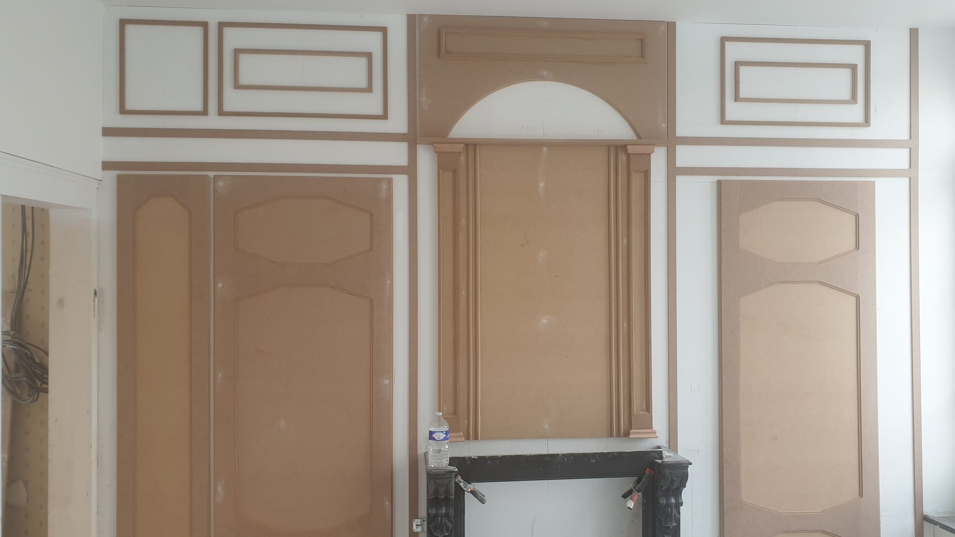 Mur en construction avec lambris, moulures décoratives et cheminée, vue de l'intérieur.