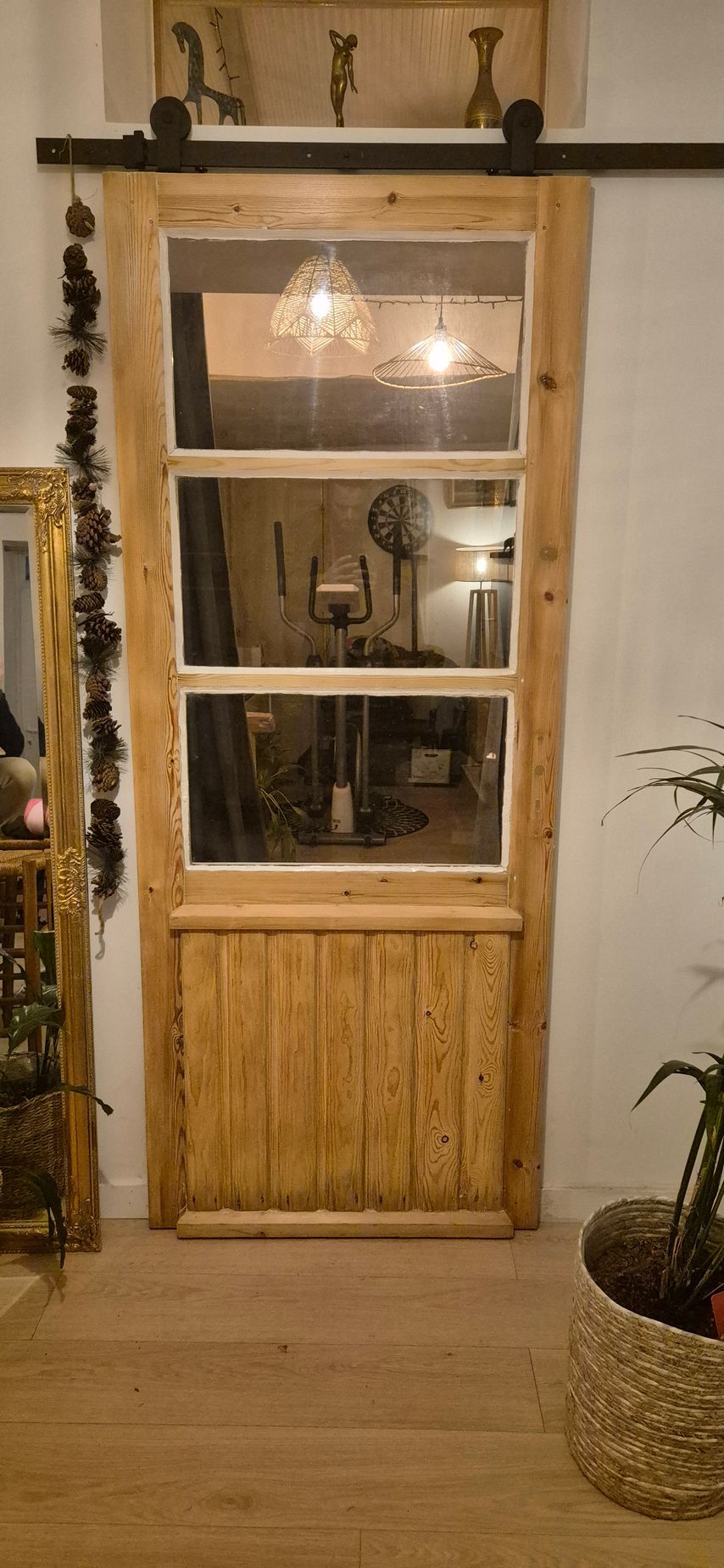 Porte coulissante en bois avec vitres, rail noir et élément décoratif en partie supérieure.